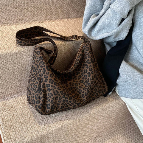 Leopard print handbag on a textured surface with a gray garment in the background