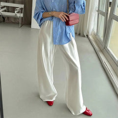 Person wearing a blue top, white pants, and red shoes in a room with a window.