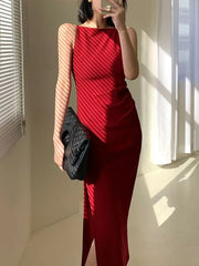 Person wearing a red dress holding a black clutch in a room with sunlight streaming in.