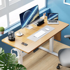Modern office desk with computer setup, chair, and plants in a bright room.