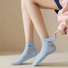 Light blue socks with a logo worn by a person on a beige background