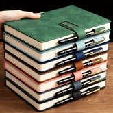 Stack of green notebooks with matching pens on a wooden surface