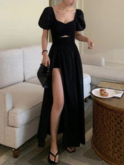 Woman in a black dress with puffed sleeves standing in a living room.