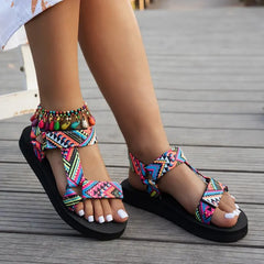 Colorful tribal sandals on feet standing on a wooden floor