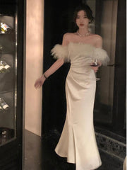 A woman wearing a white vintage-style maxi dress with a faux collar and long sleeves, featuring a trumpet/mermaid silhouette and a zipper closure.