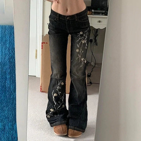 Person wearing black jeans with floral embroidery in a room.