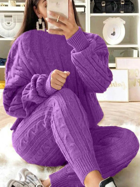 A woman sitting, wearing a purple long sleeve knitted casual two-piece top and pants set.