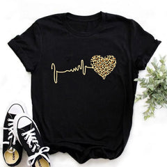 Black t-shirt with gold heart and line design, paired with white sneakers on a light background