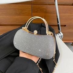 Silver glittery handbag with gold accents held by a person against a wooden background