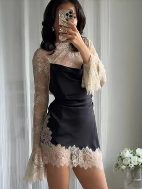 Person wearing a black dress with lace details in front of a neutral background
