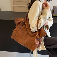 Person holding a brown leather handbag in an indoor setting