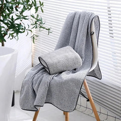 Gray textured blanket draped over a chair with a plant in the background