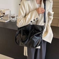 Person holding a black leather bag in an indoor setting
