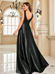 Woman in a black evening gown standing in an elegant interior setting with chandeliers.
