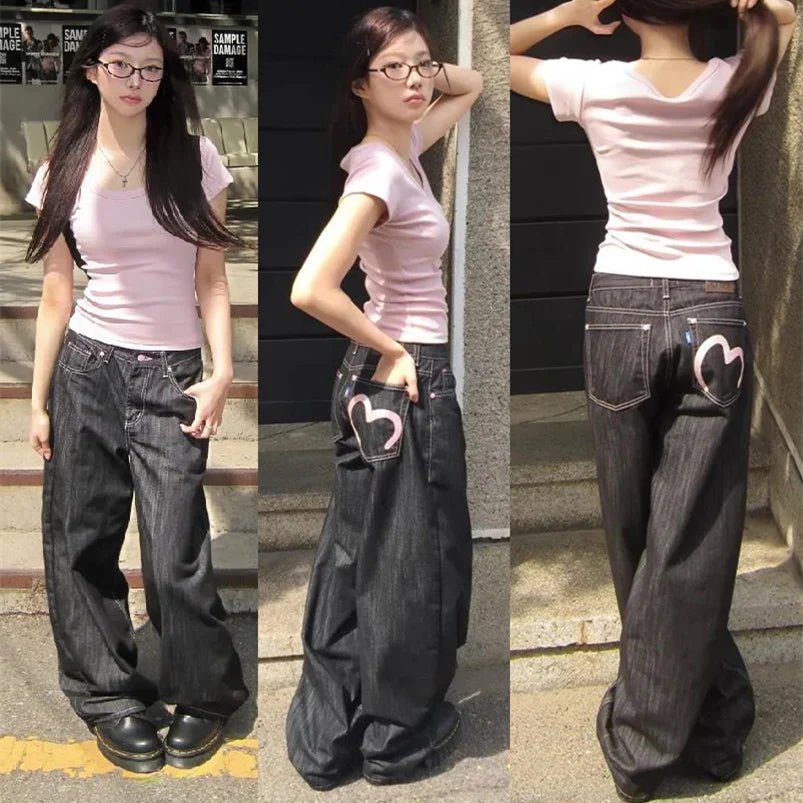 Woman wearing a pink shirt and black wide-leg jeans with heart designs, posing on steps.
