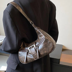 Person wearing a dark coat with a brown leather shoulder bag.