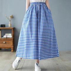 Person wearing a blue and white checkered skirt in a room with a gray wall and wooden furniture.