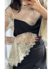 Person wearing a black top and black skirt with a beige lace shawl over shoulders.