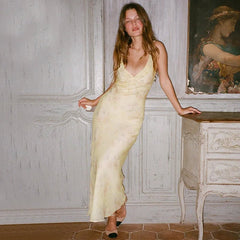 Woman in a yellow dress standing in an elegant room with classical painting.
