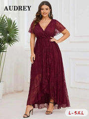 A woman wearing an elegant plus size lace dress with a V-neck, short ruffled sleeves, and an asymmetrical hemline in a dark burgundy color. The dress appears to be for formal occasions such as evening parties or weddings.