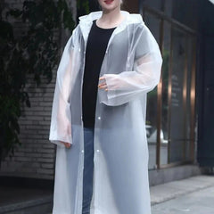 Person wearing a transparent raincoat over a black top and jeans in an urban setting.