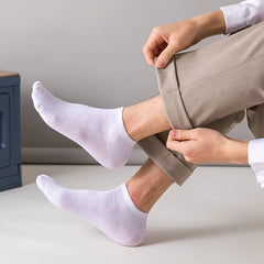 Person wearing white socks and beige pants sitting on a light-colored surface.