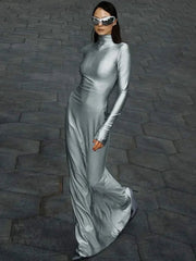 Woman in a silver dress and sunglasses standing on a stone pavement