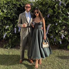 Man and woman in formal attire standing outdoors with greenery in the background