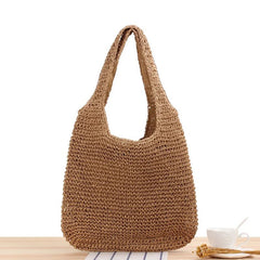 Brown woven handbag on a light wooden surface with a white background