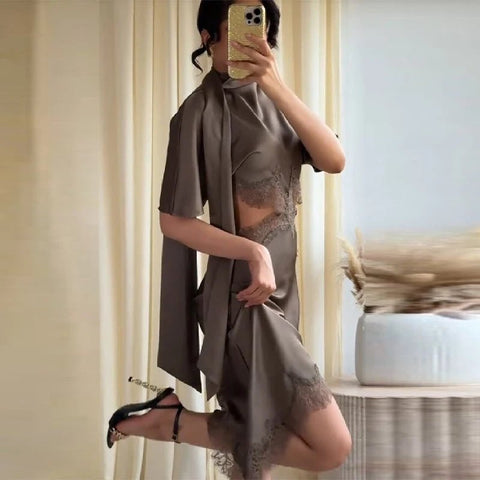 Person wearing a gray dress with lace details in a room.