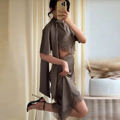 Person wearing a gray dress with lace details in a room.