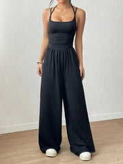 Person wearing a black jumpsuit on a plain background