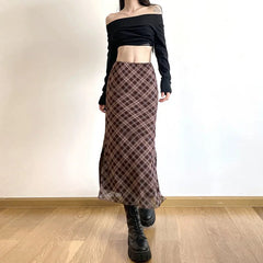 Person wearing a black off-shoulder top and plaid skirt on a plain background