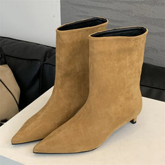 Pair of brown suede ankle boots on a light surface with a neutral background