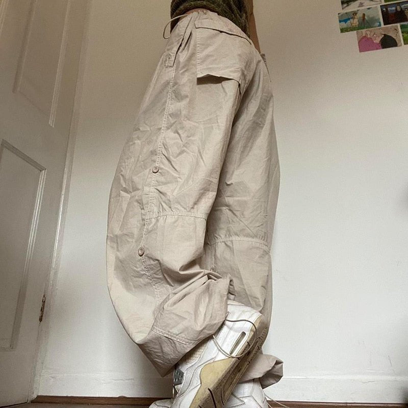 Woman wearing beige wide-leg parachute cargo pants with a drawstring closure.