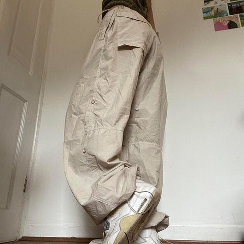 Woman wearing beige wide-leg parachute cargo pants with a drawstring closure.