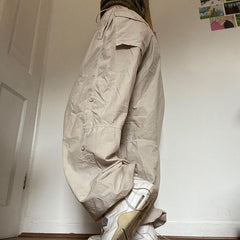 Woman wearing beige wide-leg parachute cargo pants with a drawstring closure.