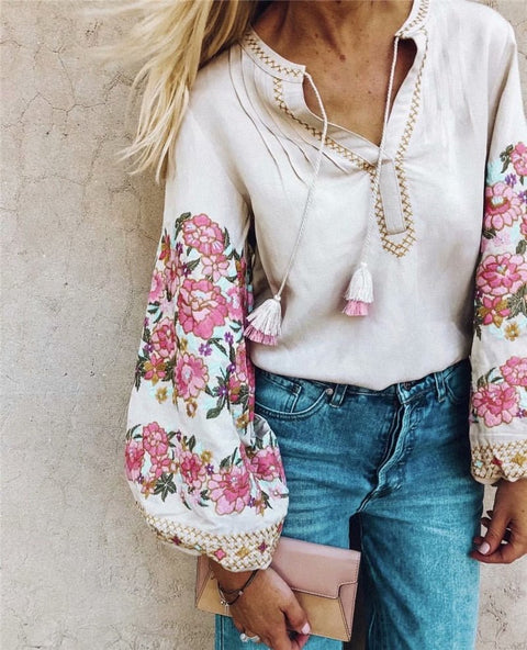 A woman wearing a white floral embroidery linen cotton blouse with full sleeves and an O-neck collar. She is accessorized with a pink scarf and jeans.
