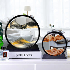A round moving sand art piece with a black outer frame and a transparent glass panel, showing colored sand creating mountain-like formations inside.