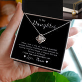 A necklace with a silver message card, featuring a gold-colored pendant with cubic zirconia crystals, presented in a black box with a lobster clasp.