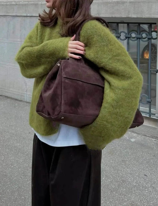 Woman wearing an oversized green O-neck knit pullover sweater with a matching bag, from Modernicities' guide to tops for every occasion