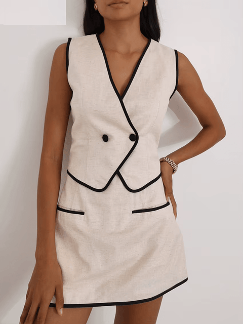 Woman wearing a beige dress with black trim against a white background