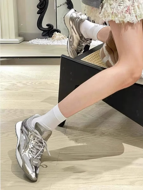 Person wearing silver sneakers and white socks sitting on a chair.