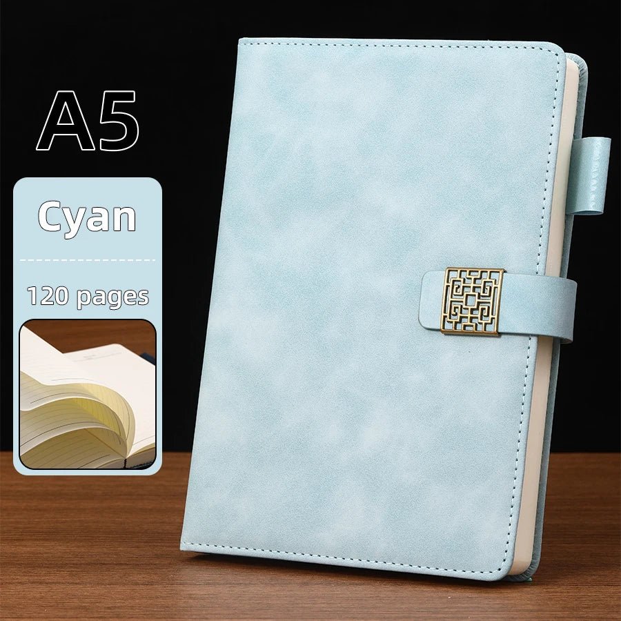 Light blue A5 notebook with gold buckle on a wooden surface and black background