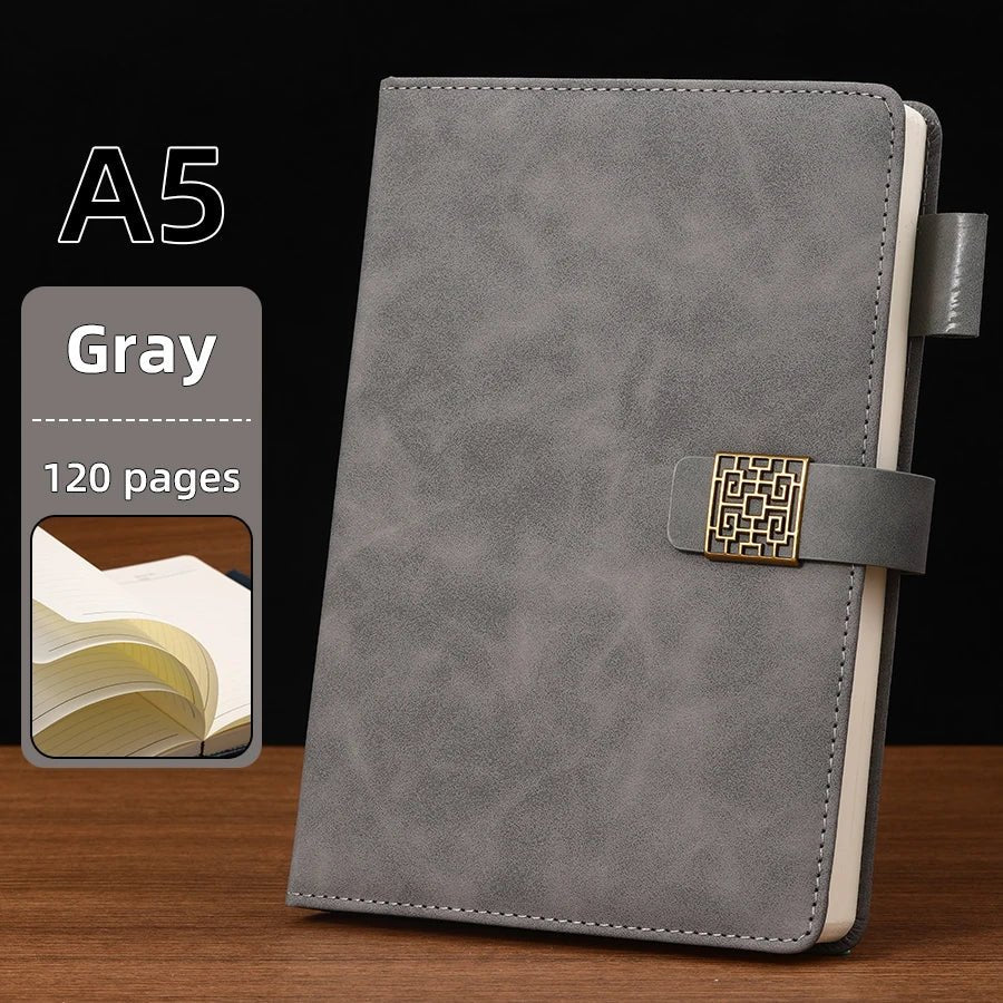Gray notebook with gold buckle on a wooden surface and black background