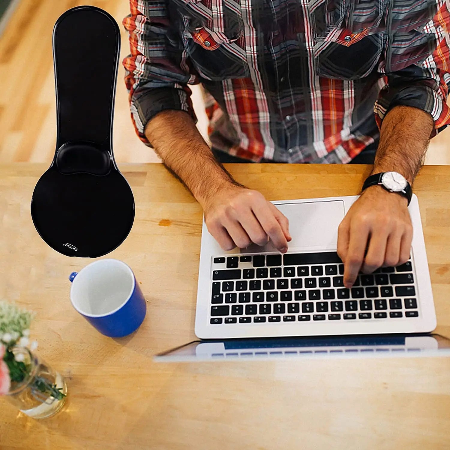 Person using a laptop on a wooden desk with a mug and Computer Arm Res.