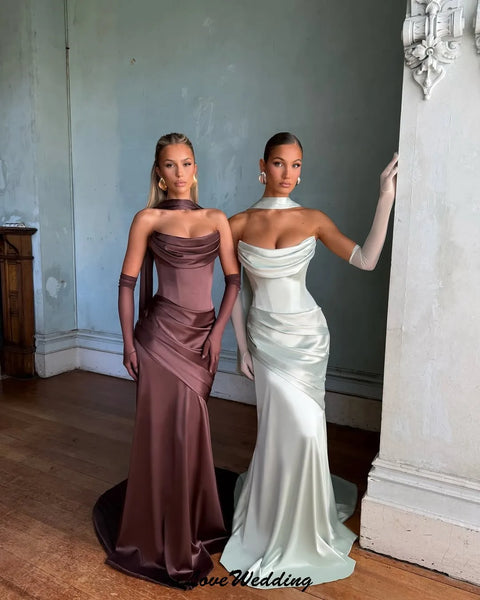 Two women in elegant evening gowns standing side by side in an indoor setting.