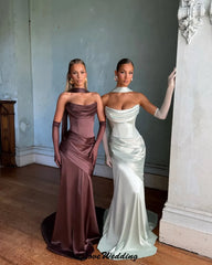 Two women in elegant evening gowns standing side by side in an indoor setting.