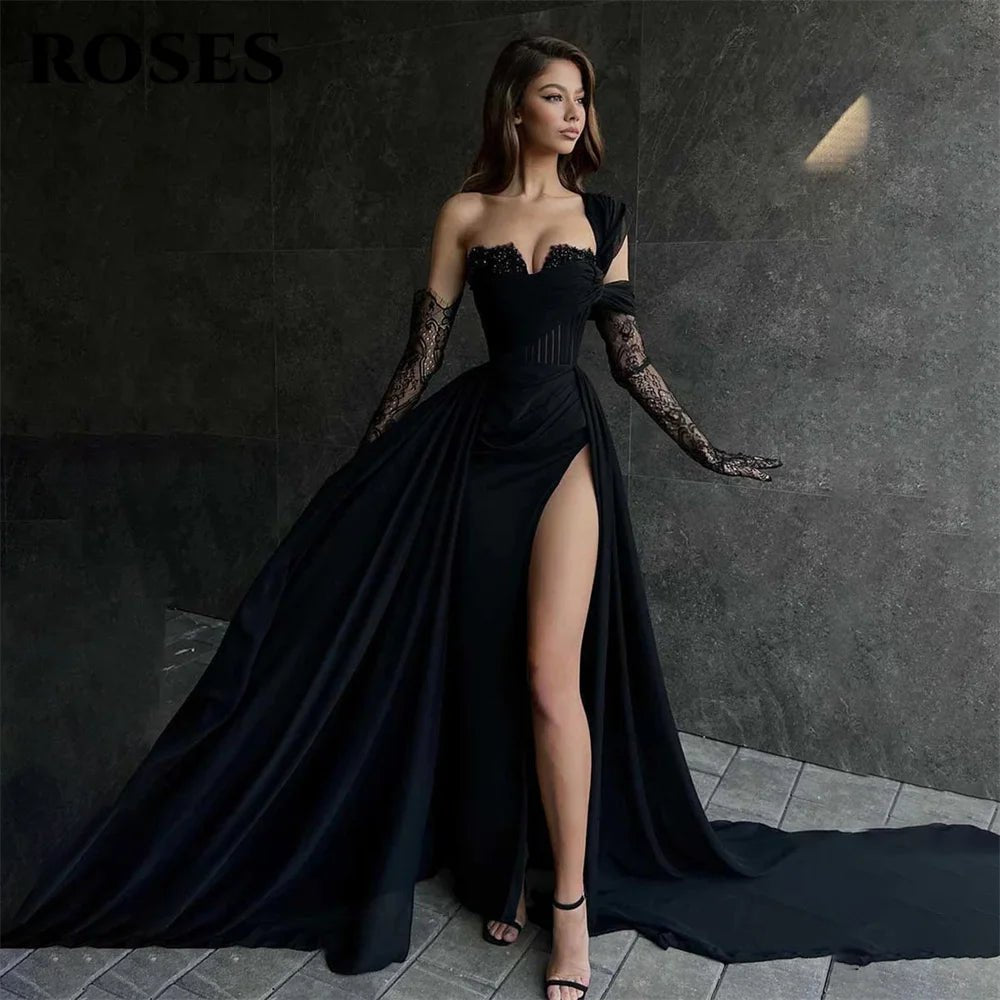 Woman in a black evening gown with lace sleeves against a dark background