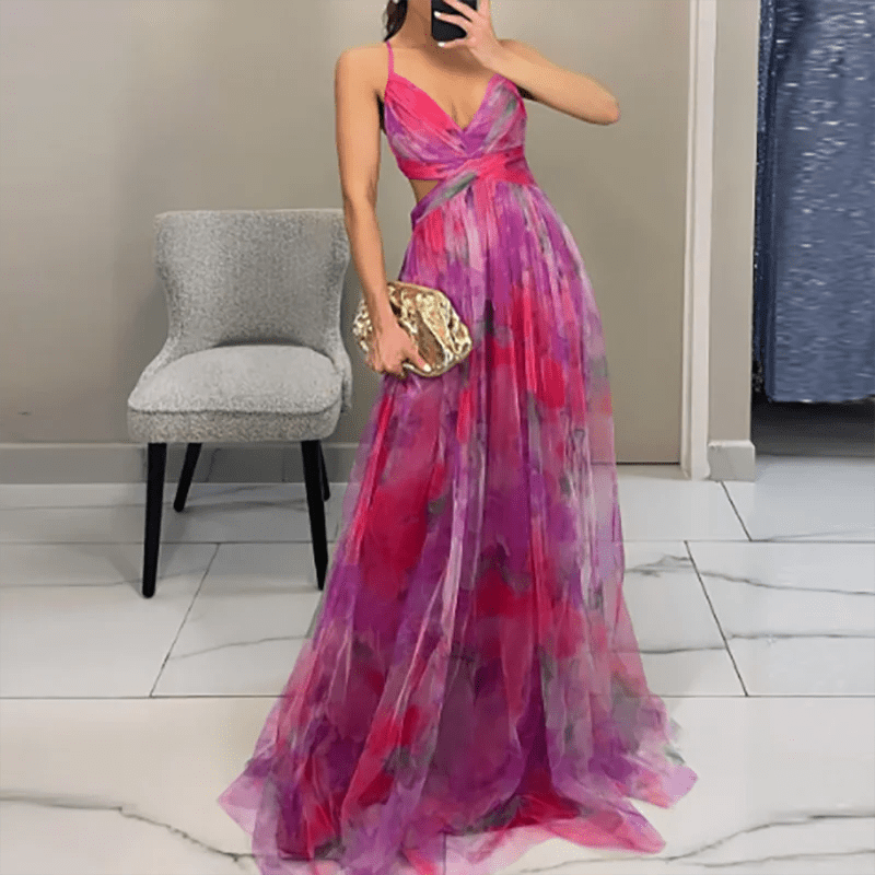 Woman wearing a colorful dress holding a gold clutch in a room.